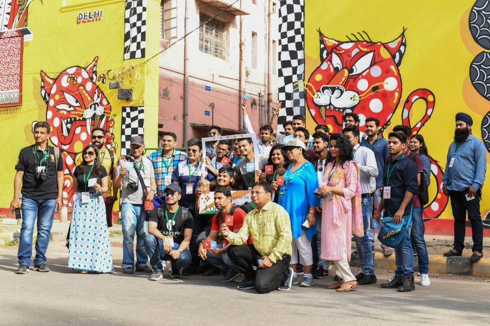 Caption: A photo of all the participants in the meet-up in front of a street mural with two red cats. (Local Guide @Explore_Keshav)