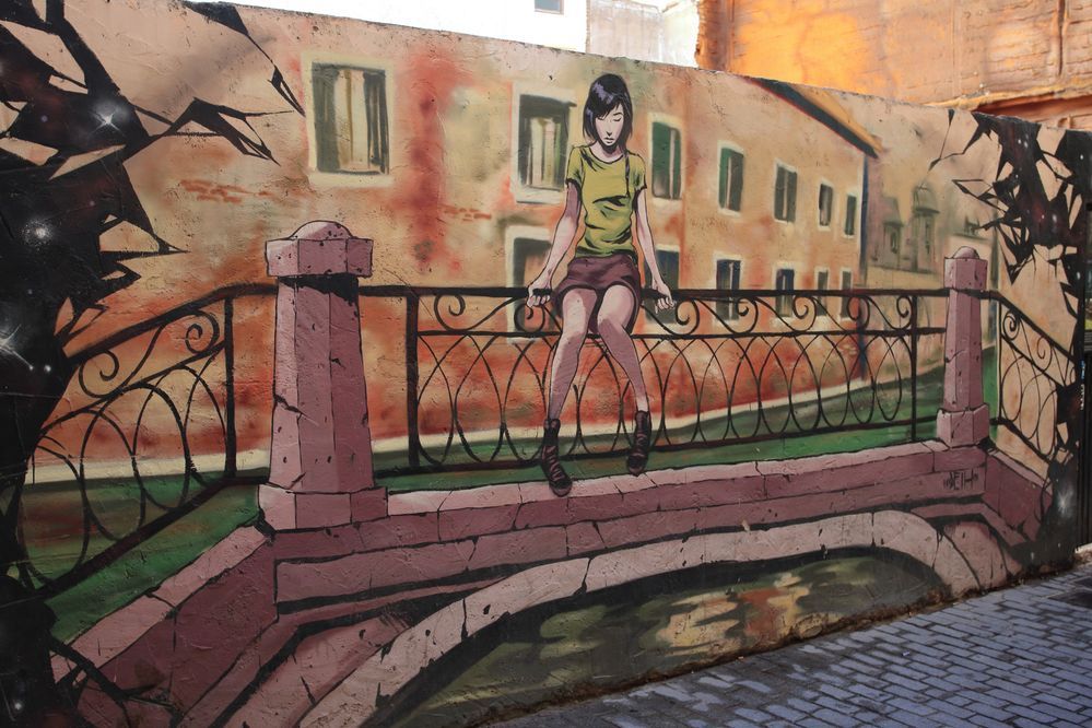 Caption: A photo of a graffiti showing a girl sitting on bridge. (Local Guide Euler_Tourist)