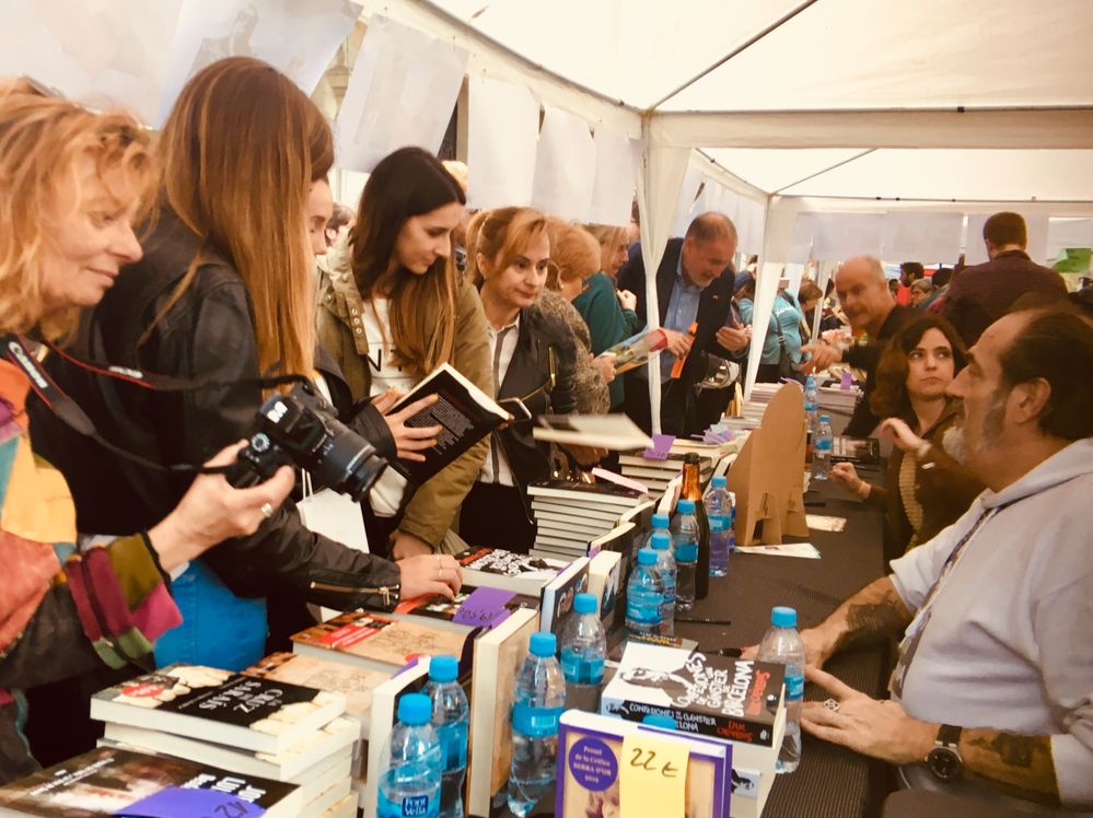 Caption: A group of people at a book signing event in the street.