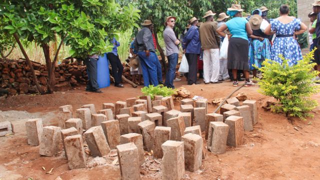 A photo showing some of the bricks that have been made from the water system developed in the village. The people of the tour listen to the talks ahead. Photo cred: Local Guide Leora Hart