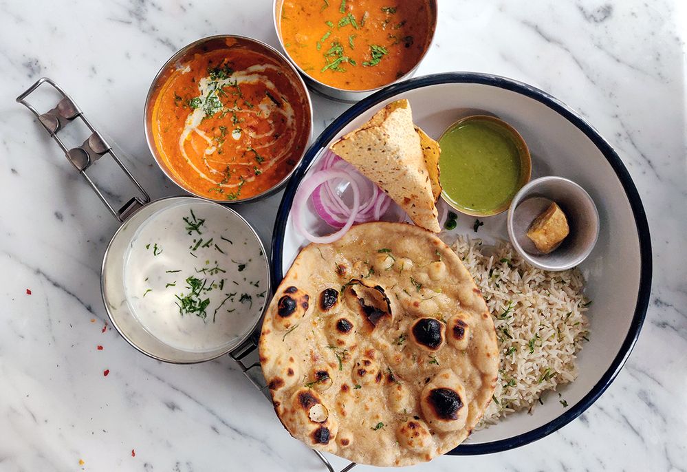 Caption: A photo of an overhead view of Indian thali on a marble table with various dishes and naan at Echoes Kolkata in West Bengal, India. (Local Guide Pooja Agrawal)