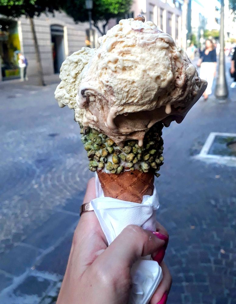 Caption: A photo of pistachio and milk chocolate gelato in a waffle cone, decorated with pistachio chunks. (Local Guide @MoniDi)