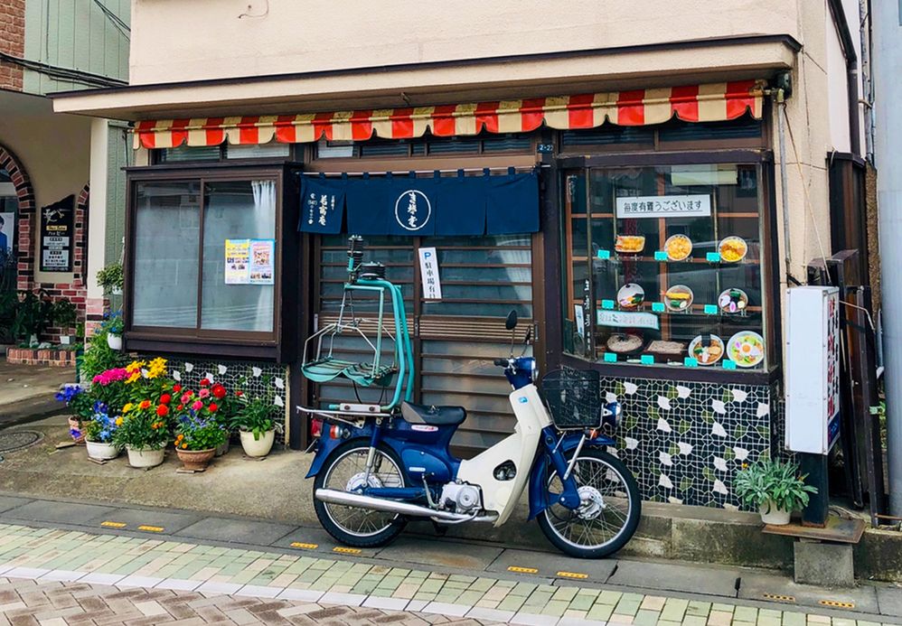 Caption: A photo of a motorbike and potted flowers outside of a soba noodle shop in Konosu Japan. (Local Guide 界外宏明)