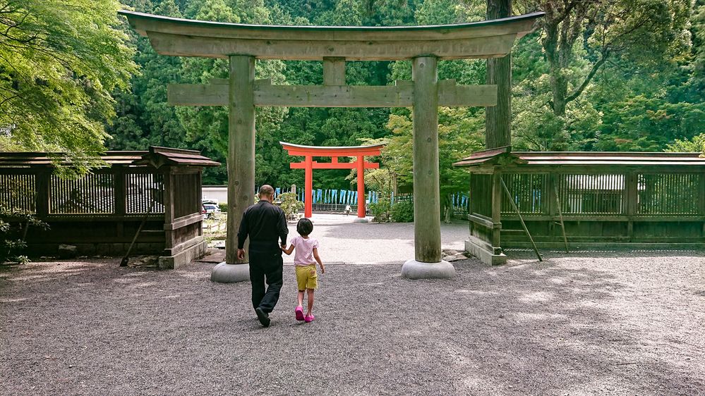 Caption: A photo of the back view of a man and child holding hands and walking towards a shinto shrine at Niukawakami Lower Shrine in Nara, Japan. (Local Guide 池松恭子)