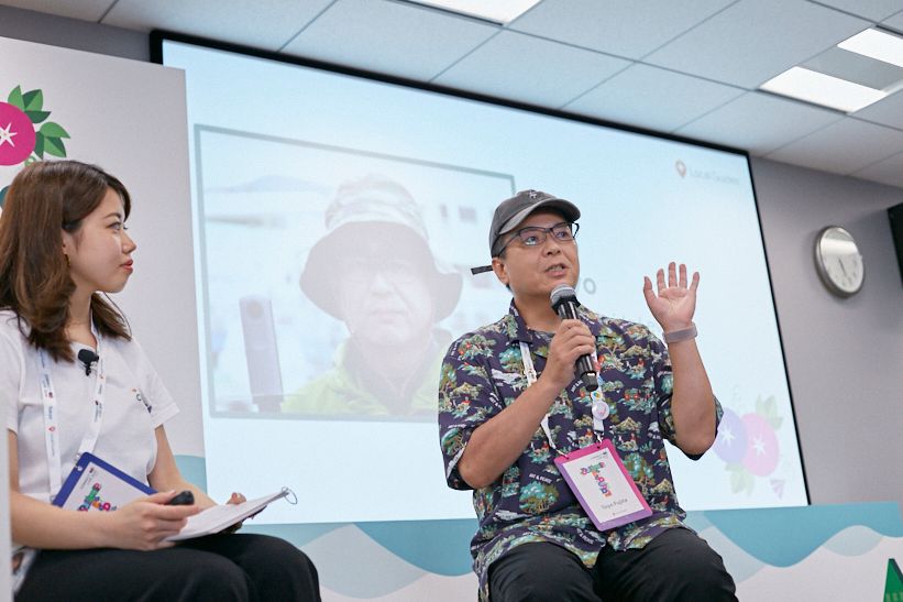 Caption: A photo of a Googler Azusa Nakazawa interviewing Local Guide Toyo Fujita on-stage at Connect Live Tokyo.