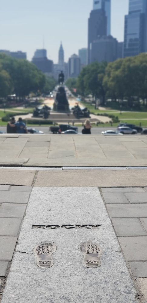 Caption: a photo from the top of the Rocky's stairs in Philadelphia Museum of Art showing Rocky's footprints and The Oval monument on the background. (Local Guides @FelipePk)