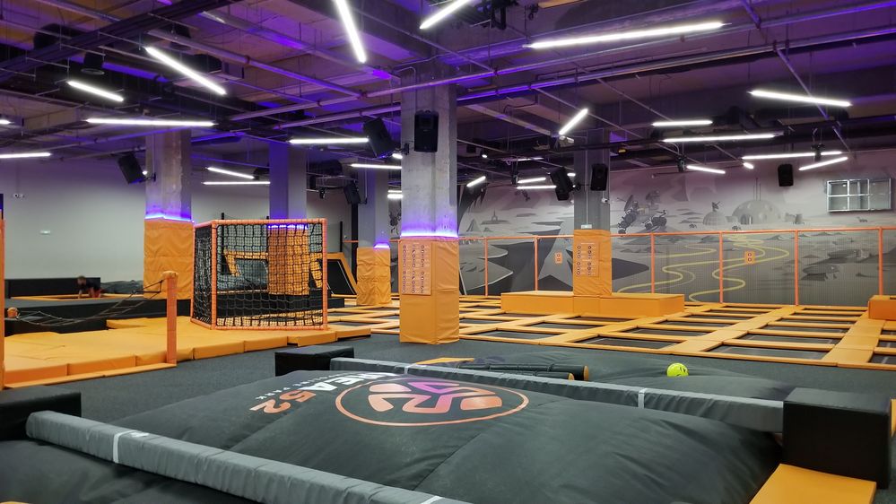 Caption: A photo taken inside Area 52 Trampoline Park showing the trampolines and other activity areas, surrounded by orange safety mattresses. (Local Guide Vesko Mutafchiev)