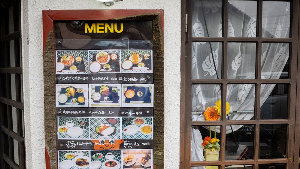 Caption: A photo of a menu with photographs of plates of food and prices next to a window outside a restaurant in Nagano, Japan. (Local Guide Kouzi Kasai)