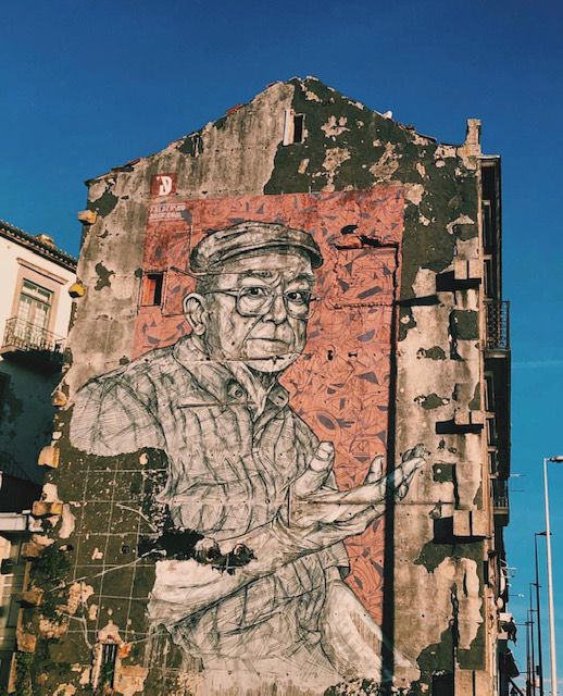 Legenda: a photo de uma arte de rua de um senhor feito na parede de um prédio parcialmente arruinado. (Local Guide @FelipePk)