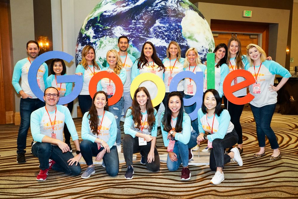 Caption: A photo of some members of the Local Guides team in front of a giant globe and Google letters.