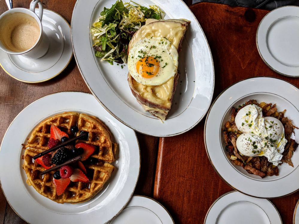 Caption: A photo of several plates of food including waffles with berries, eggs on toast, and poached eggs at Petite Boucherie in New York, NY. (Local Guide Irene K.)