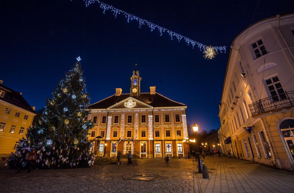 Caption: A photo of a decorated Christmas tree at Tartu Külastuskeskus with strings of holiday lights on buildings at night in Tartu, Estonia. (Local Guide Андрей Явнашан)