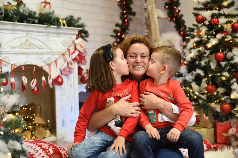 Caption: A photo of Google Moderator @MoniV hugging her daughter and son. There are Christmas decorations in the background.