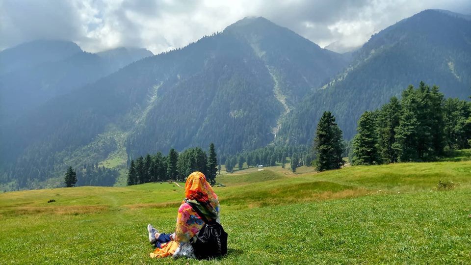 Caption: A photo of Sumaiya sitting on a green field and looking at some mountains in the distance. (Courtesy of Local Guide @SumaiyaZafrinC)