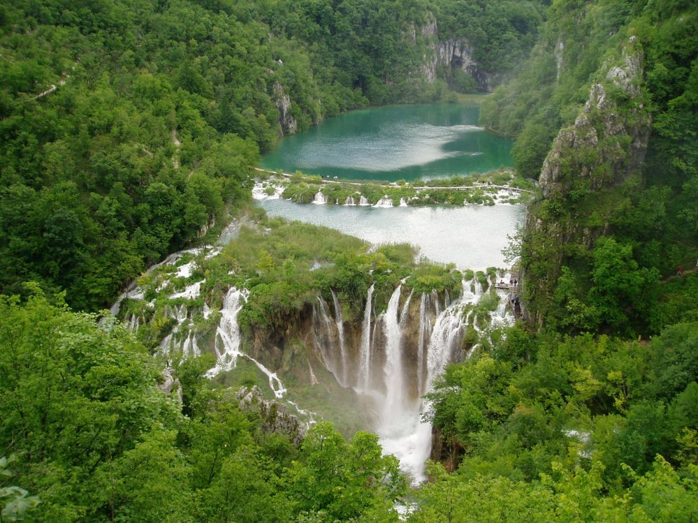 Caption: A photo of a big waterfall surrounded by a green forest at the Plitvice Lakes National Park in Croatia. (Local Guide @ArtistHR)