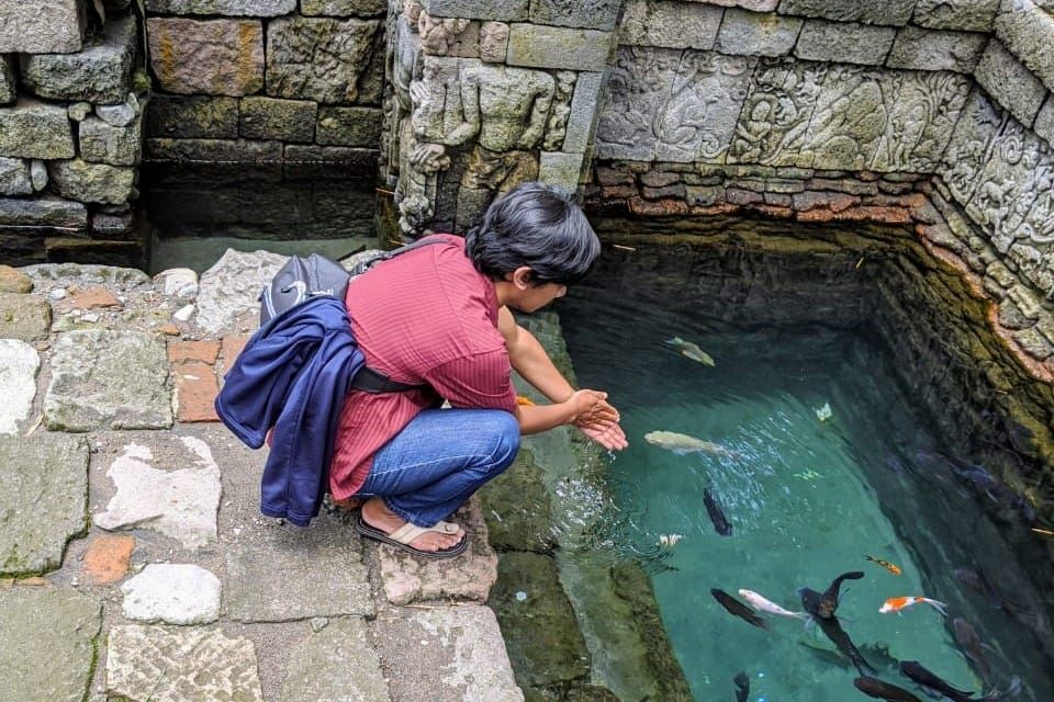 caption: A Local Guide wash his hand at Royal bathing pool in Penataran Temple (Local Guide Nunung Afuah)