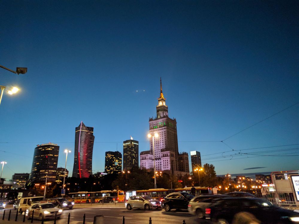 Caption: A night photo of the Palace of Science and Culture in Warsaw and the surrounding buildings. (Local Guide @MoniDi)