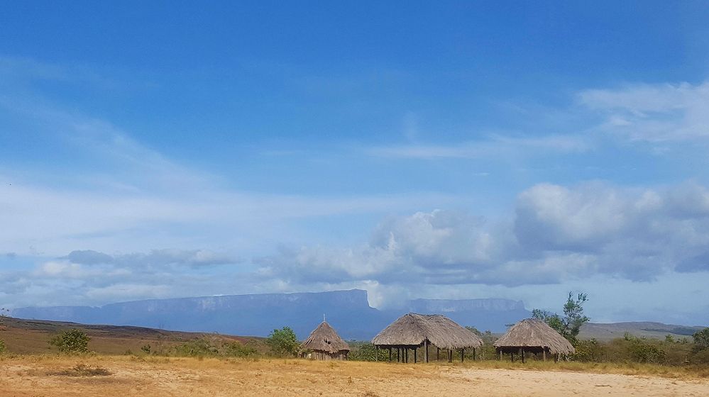 Caption: Some indigenous huts in front of the famous Monte Roraima in the background.