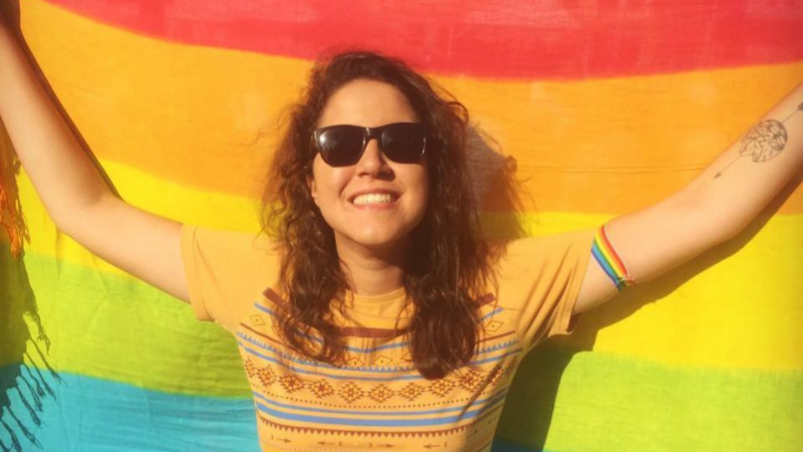 Caption: A photo of Carolina Maria Soares Lima holding up a rainbow flag to celebrate Pride. (Local Guide Carolina Maria Soares)