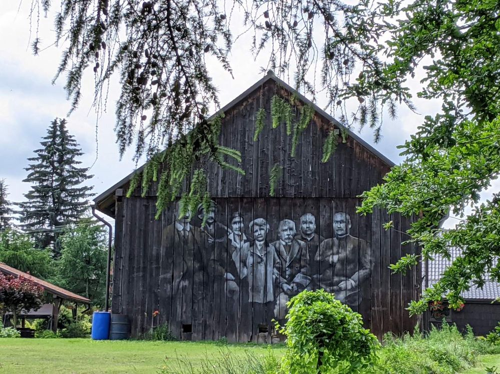 Wooden barn with a black and white painting presenting a group of people.