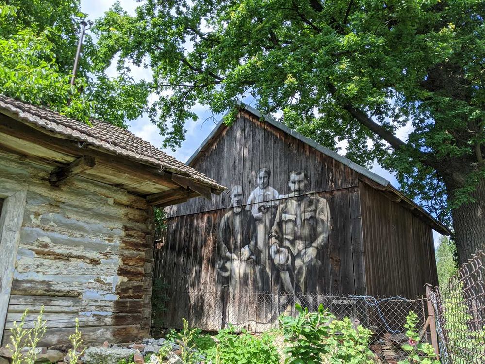 Two men with a kid painted on the barn.